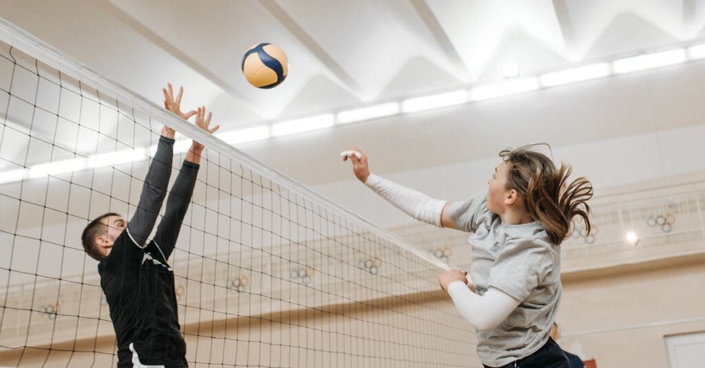 Two athletes engaged in a thrilling volleyball match indoors, showcasing competitive spirit and energy.