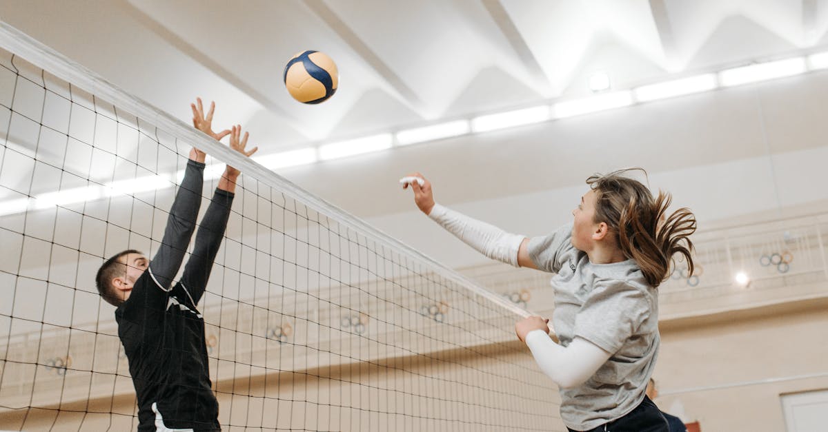 Two athletes engaged in a thrilling volleyball match indoors, showcasing competitive spirit and energy.